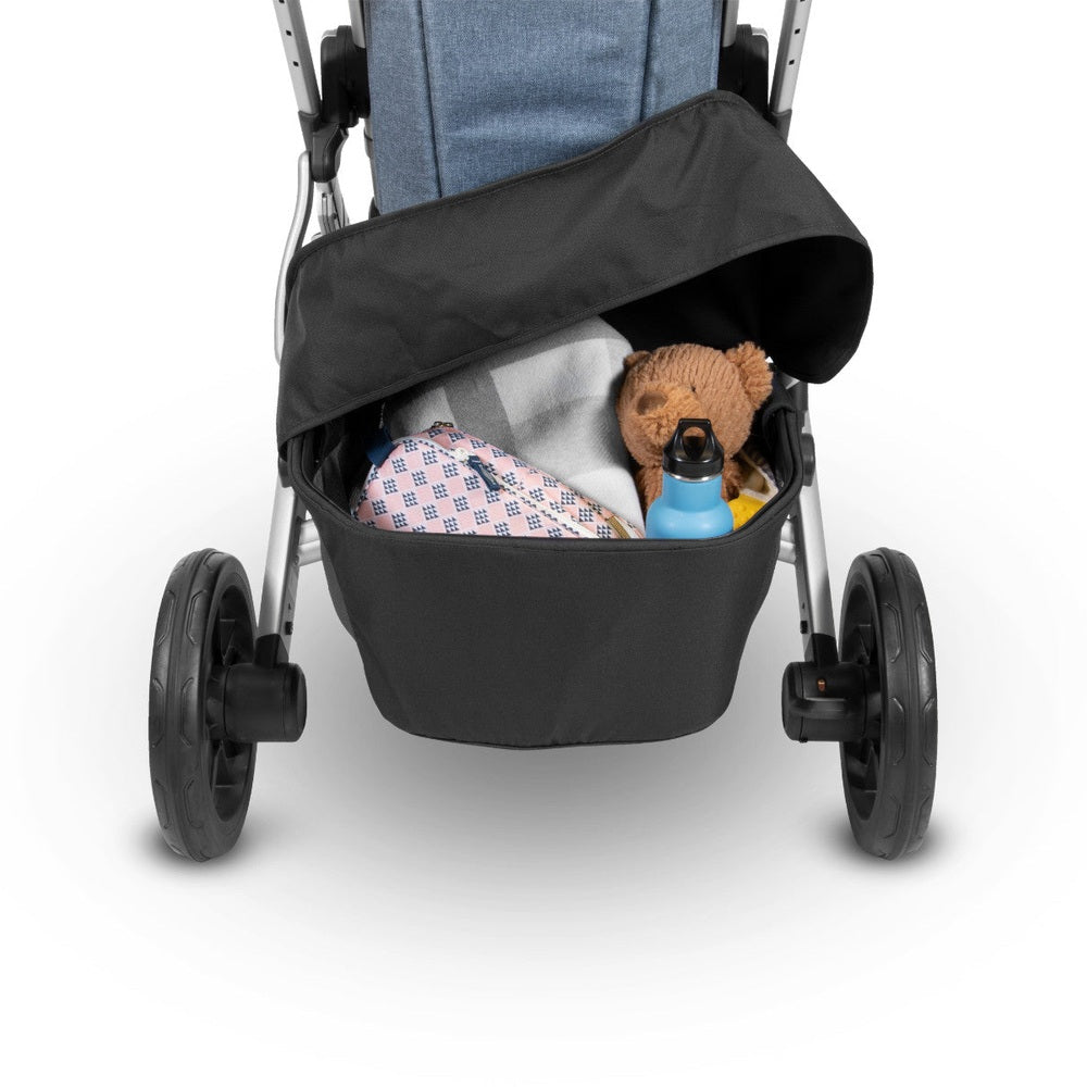 UPPAbaby Cruz V2 basket cover in black stroller basket with blue bottle, teddy bear, and blankets