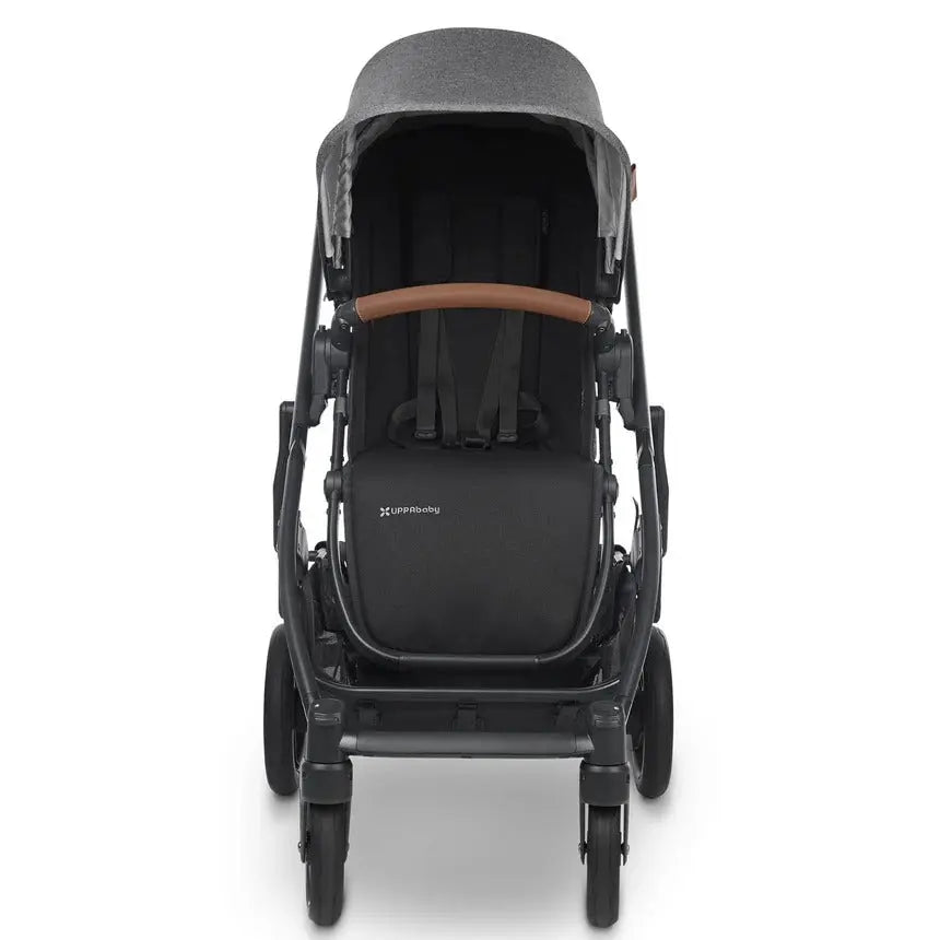 Uppababy Cruz V2 Stroller in black with brown leatherette handle and gray canopy, rear view with visible safety harness.