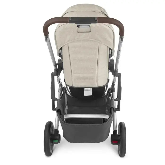Uppababy Cruz V2 Stroller, beige fabric with brown leatherette handle, rear storage basket visible from the back.