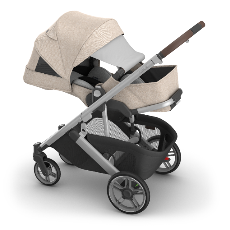 UPPAbaby Cruz V3 stroller with bassinet in beige fabric, gray frame, brown leather handle.
