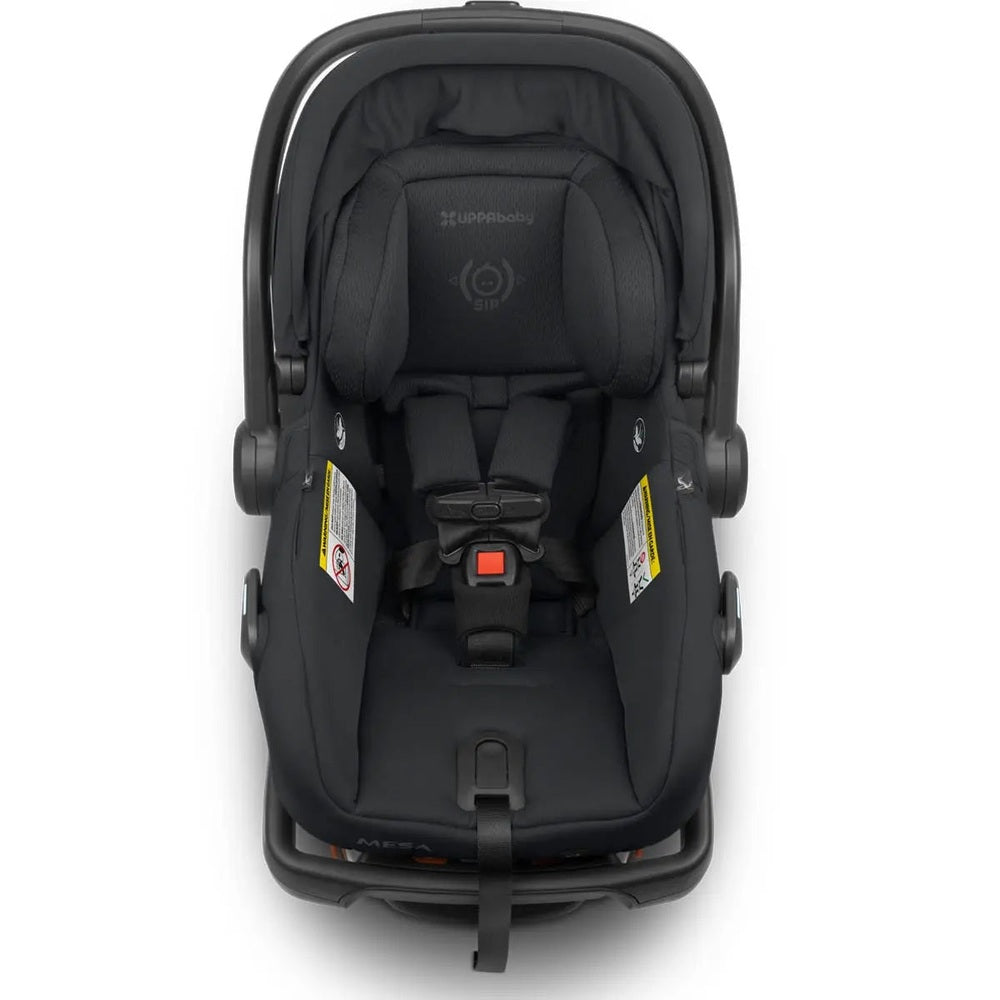 Uppababy Mesa V2 infant car seat in black, child strapped into the padded head support and 5-point harness.