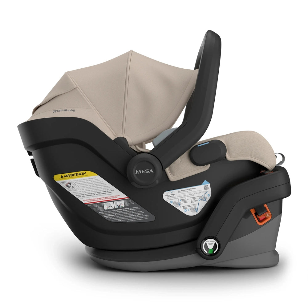 UPPAbaby Mesa V3 infant car seat in beige with black base and handle, showing secure latch and indicators.