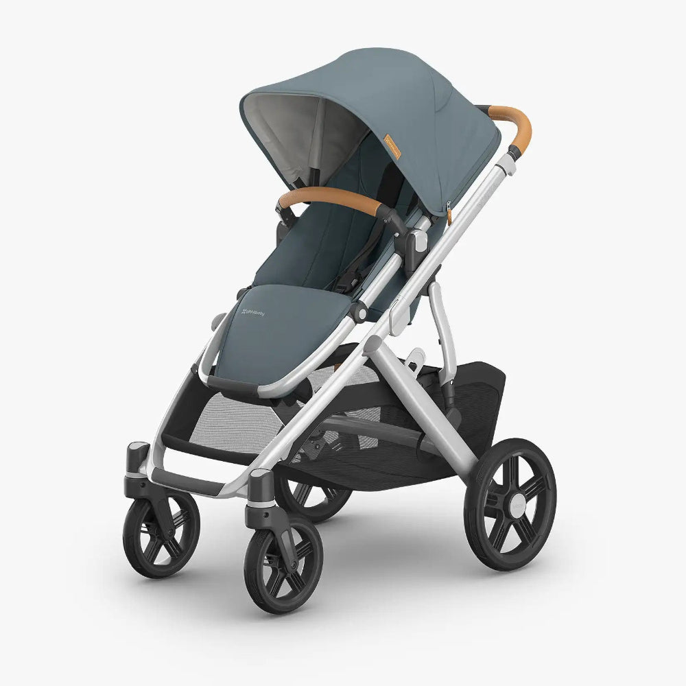 Uppababy Vista V3 Stroller in blue-gray with tan leather handlebar, canopy extended for shade.