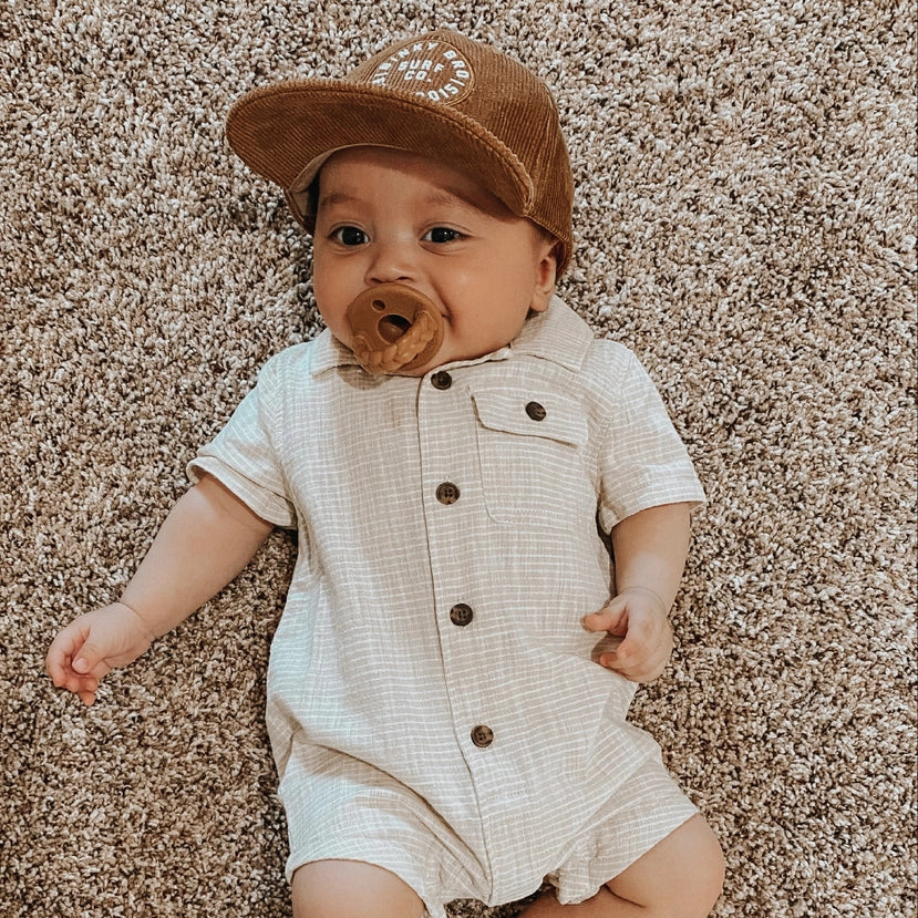 baby romper in beige check fabric with brown corduroy hat and pacifier