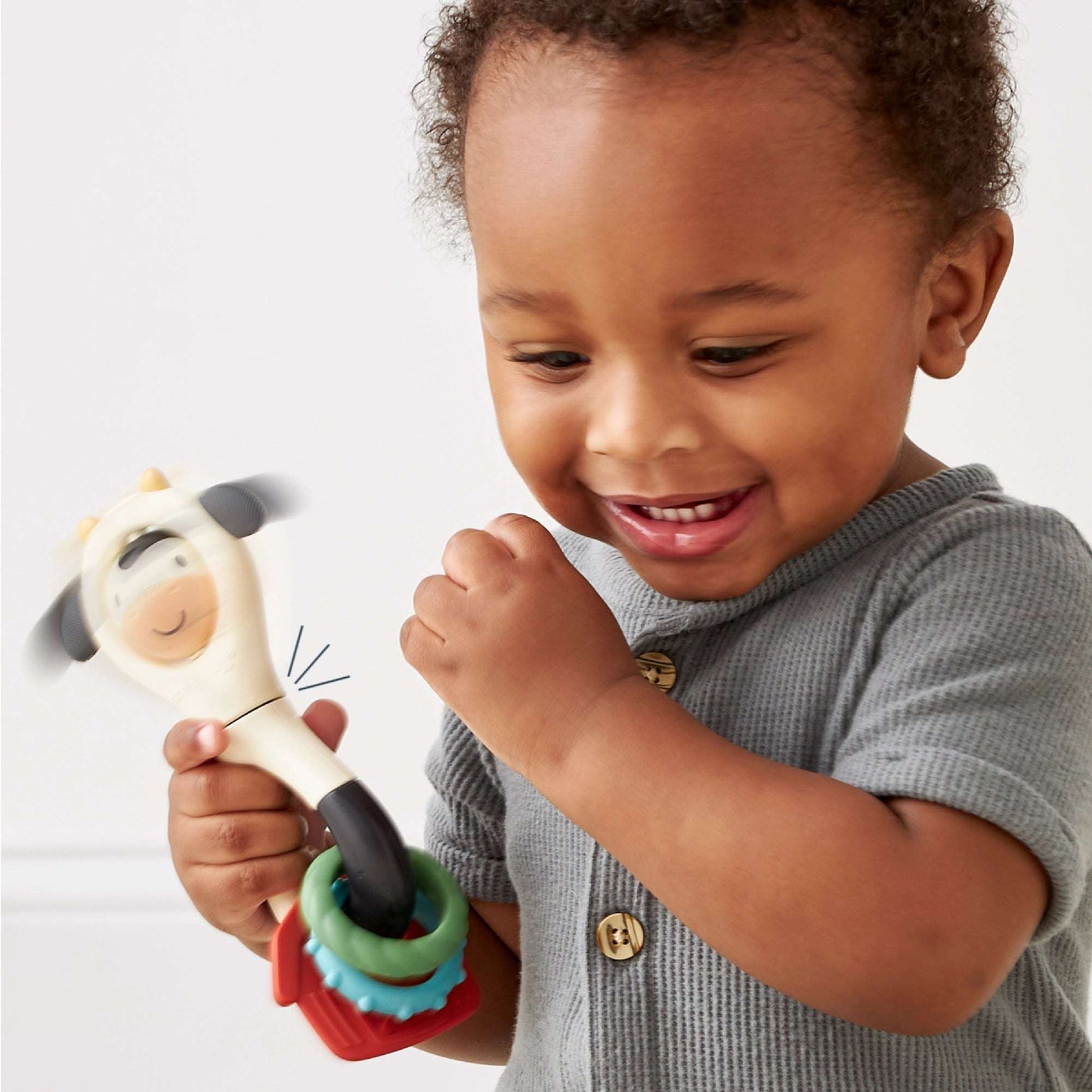 Itzy Spinner teething toy; cream animal head with black accents, stackable silicone rings in green, blue, red