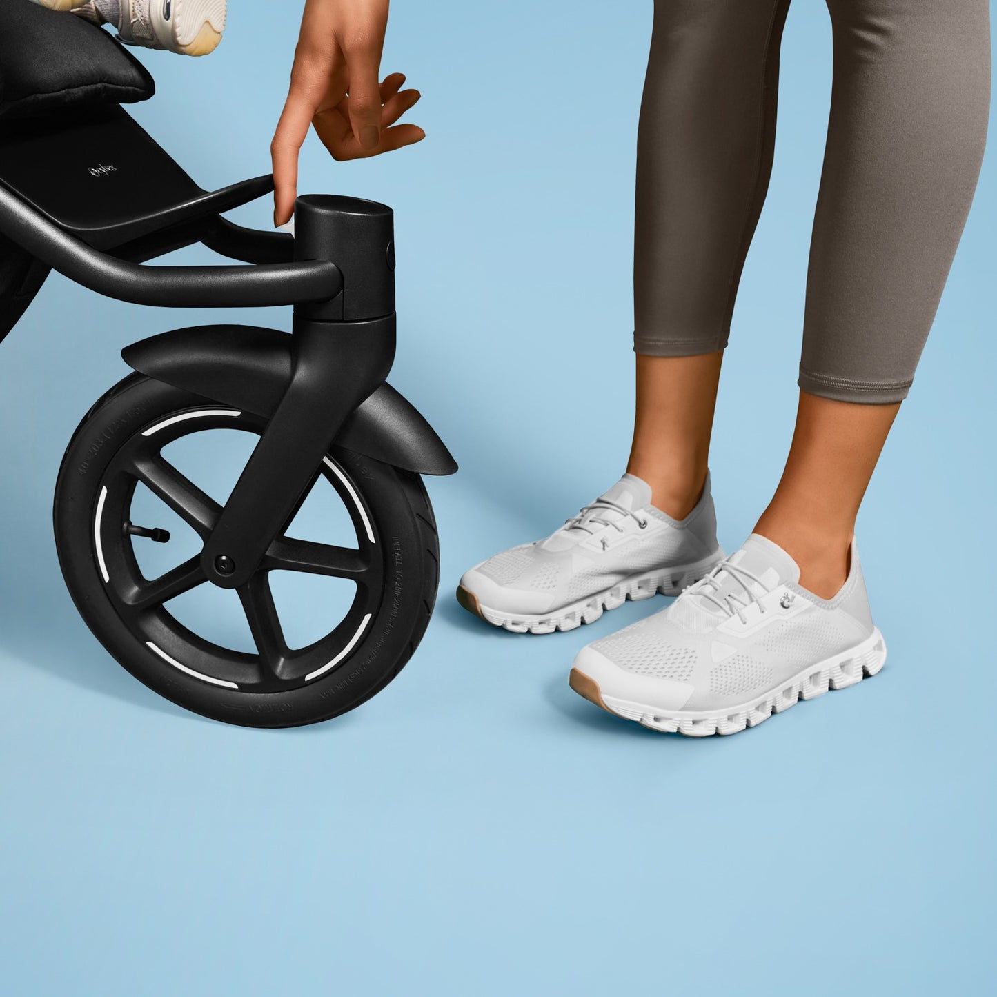 Cybex Avi Spin All Terrain Stroller in black, parent adjusting the front handle near the large wheel.