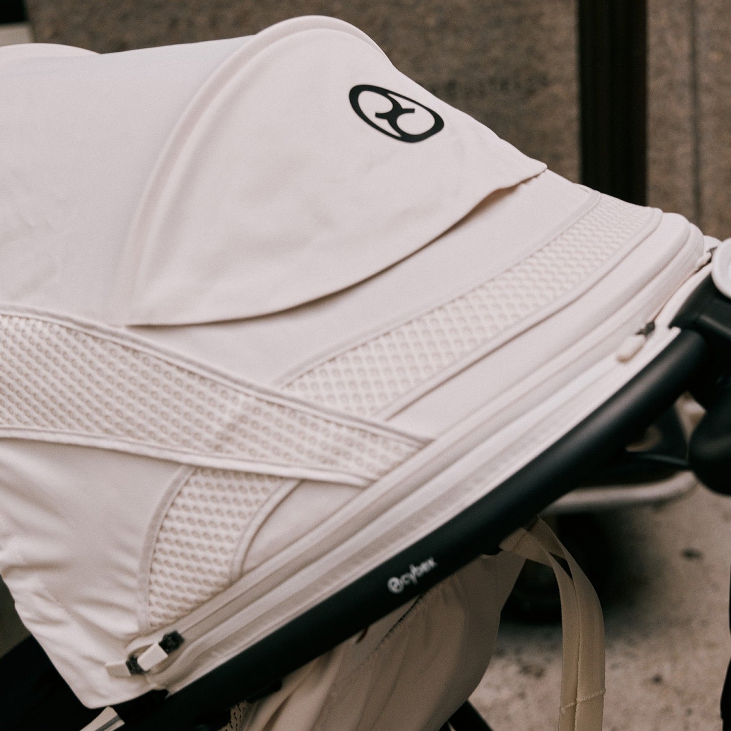 CYBEX Avi Spin All Terrain Stroller in white with mesh panels being pushed along a sidewalk.