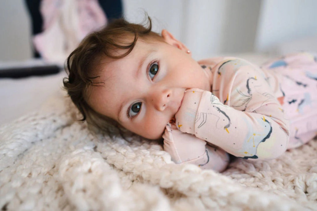 Loulou Lollipop Sleeper Unicorn Ballet: a cozy pink baby sleeper with unicorn prints, lying on a fluffy rug.
