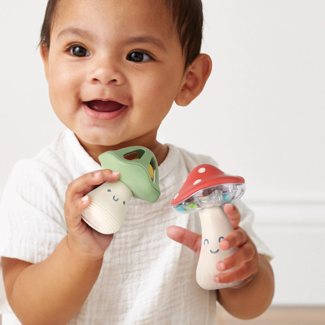 Itzy Ritzy Itzy Mini Maracas pair with green and red mushroom tops, baby holding